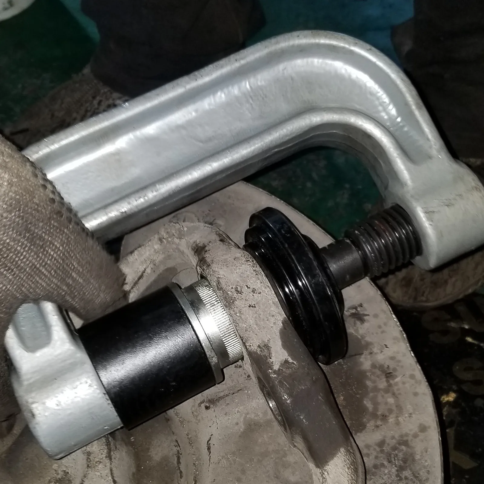 Mecánico que utiliza el kit de rótula VEVOR en un componente de suspensión sucio.