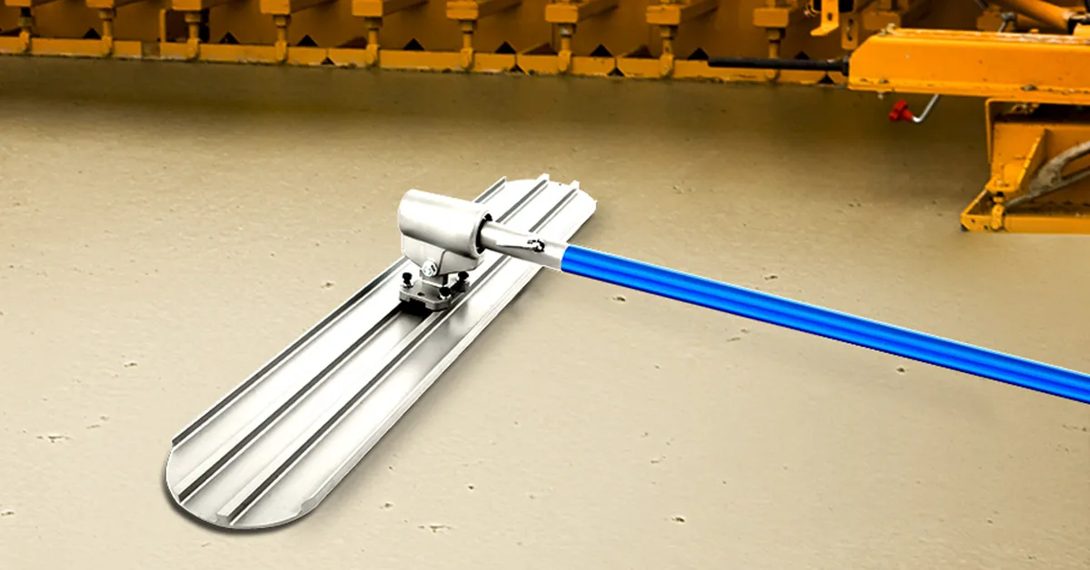 bull float with blue handle and silver blade smoothing concrete floor near yellow machinery.