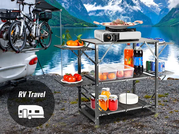 Autocaravana junto a un lago con mesa de cocina de camping VEVOR, provista de comida y bebidas, bicicletas montadas.