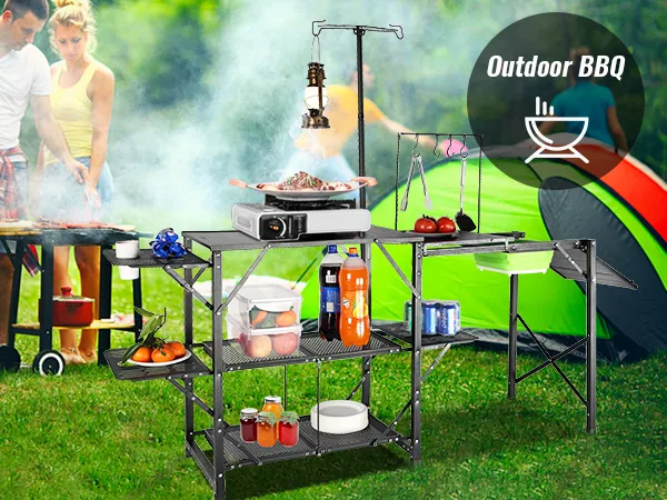 VEVOR camping kitchen table at an outdoor bbq with tents and cooking setup in a grassy park.