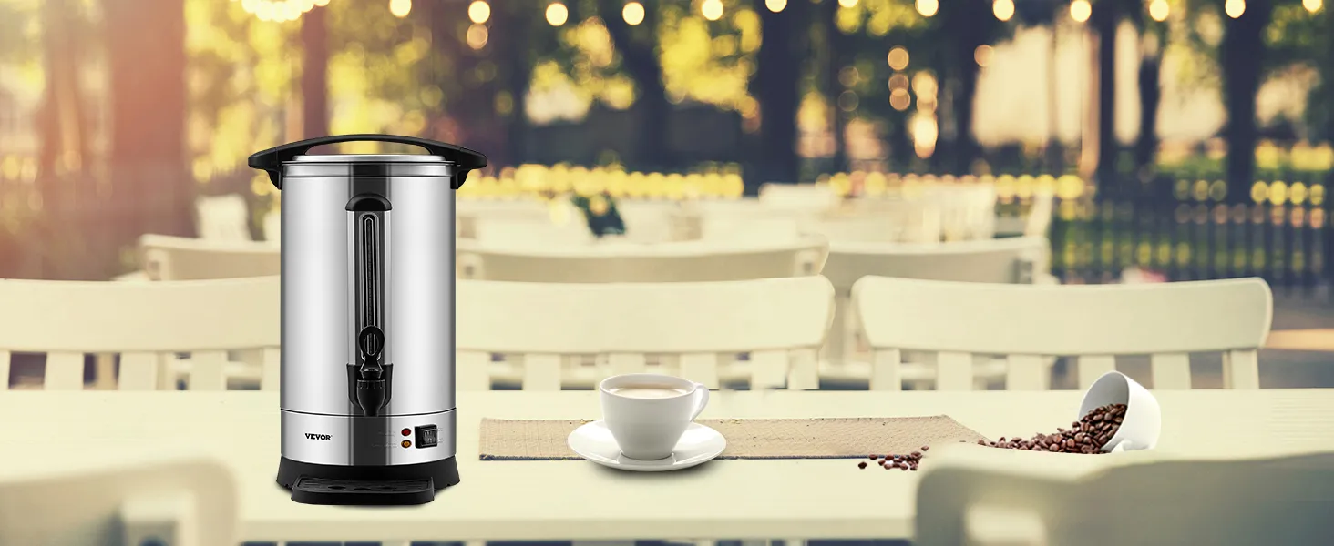 Cafetera VEVOR sobre una mesa con granos de café derramados y una taza, ubicada en un entorno de cafetería al aire libre.