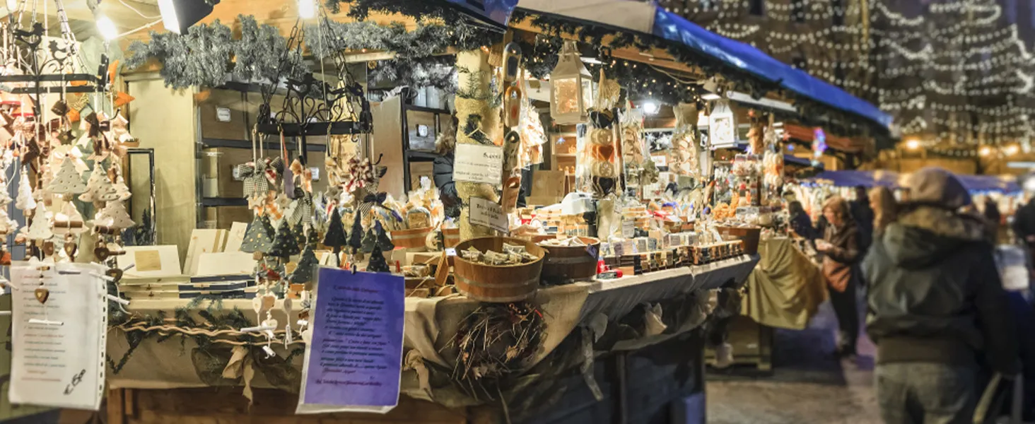 bustling holiday market with festive decorations and vibrant stands under twinkling lights at night.