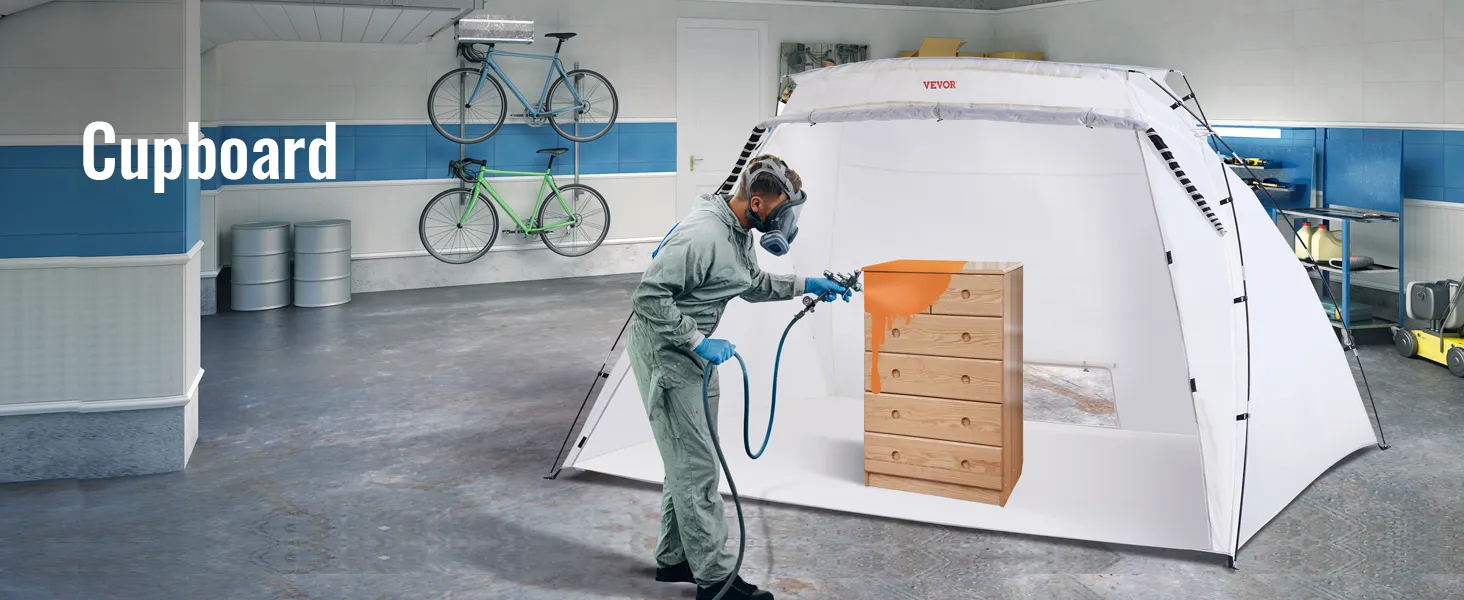 person using VEVOR portable paint booth to spray paint a wooden cupboard in a clean, organized garage.