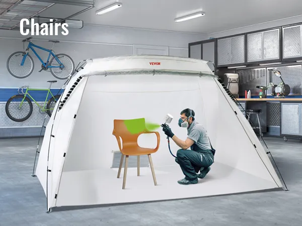 VEVOR portable paint booth used in a garage to spray paint a chair with green paint, bicycles in background.