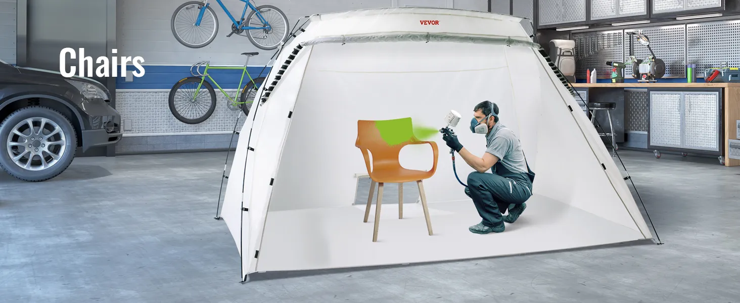 VEVOR portable paint booth used in a garage to spray paint a chair with green paint, bicycles in background.