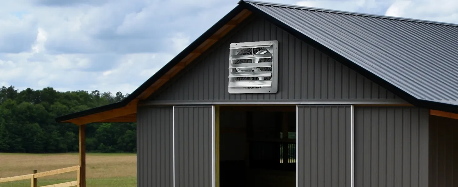 VEVOR shutter exhaust fan installed on a gray barn with a metal roof under cloudy sky.