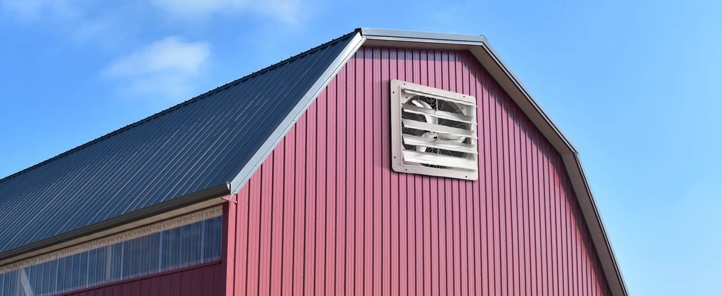 red barn with a VEVOR shutter exhaust fan on the side under a clear blue sky.