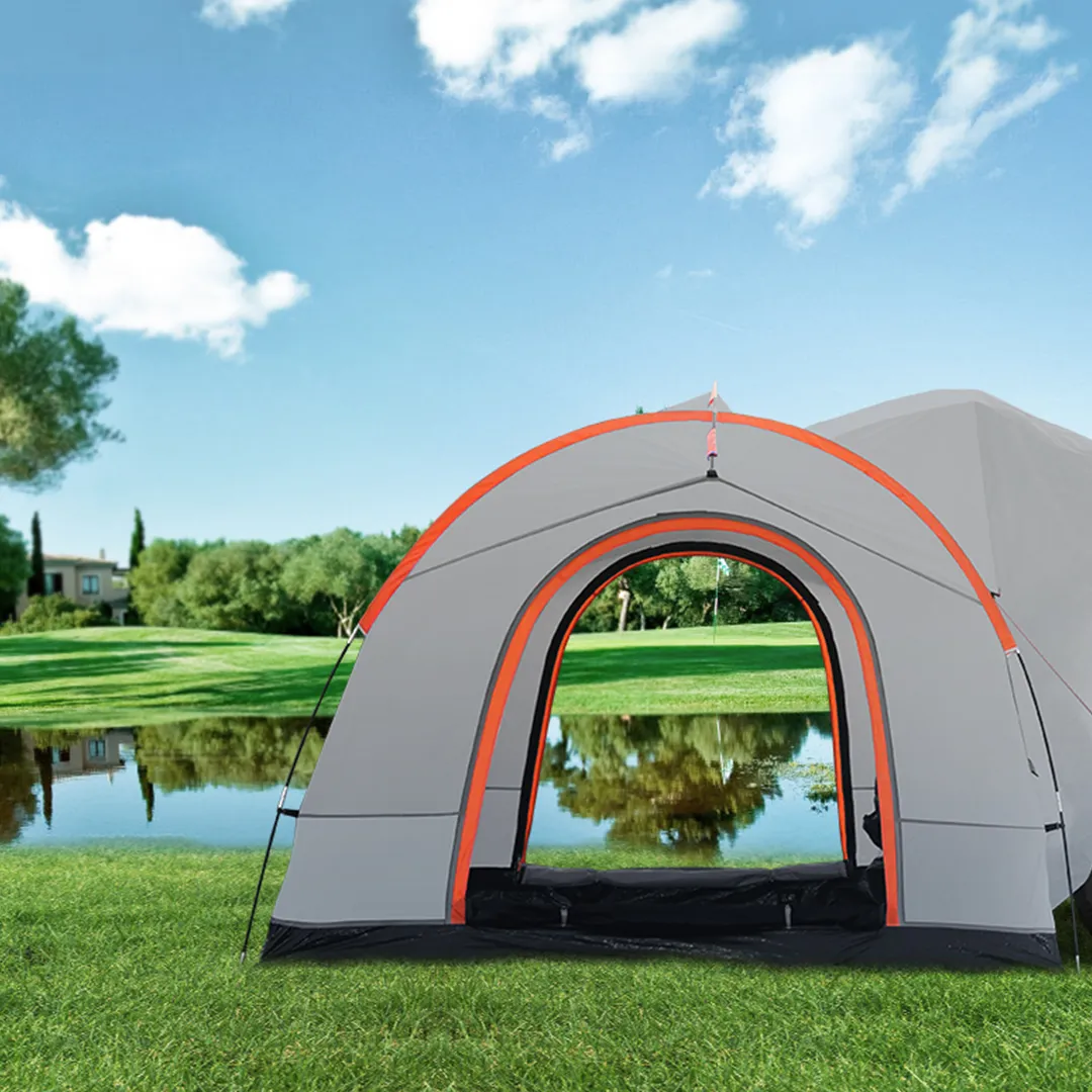 VEVOR suv camping tent setup on green grass near a serene lake under a bright blue sky with scattered clouds.