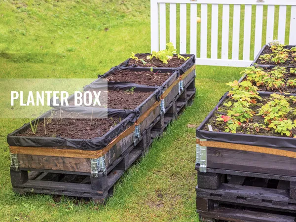 raised planter boxes on grass, partially filled with soil and seedlings. text overlay: "planter box".