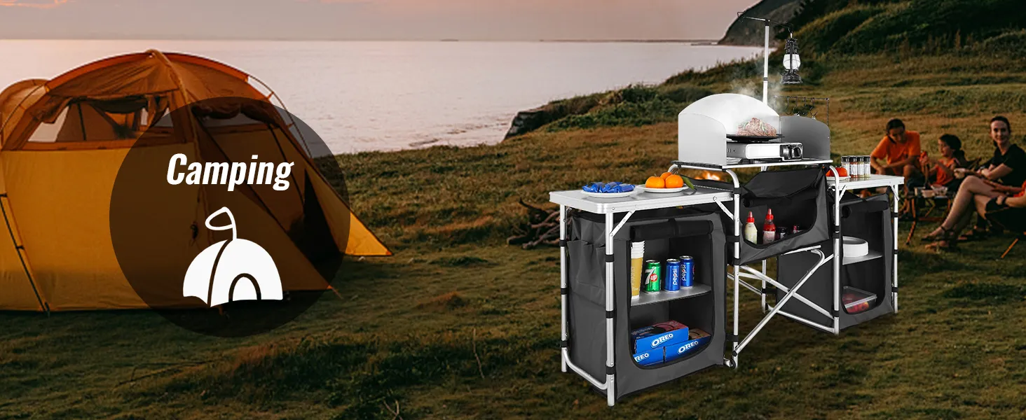 VEVOR camping kitchen table set up near a tent by the sea with supplies and food for outdoor cooking.