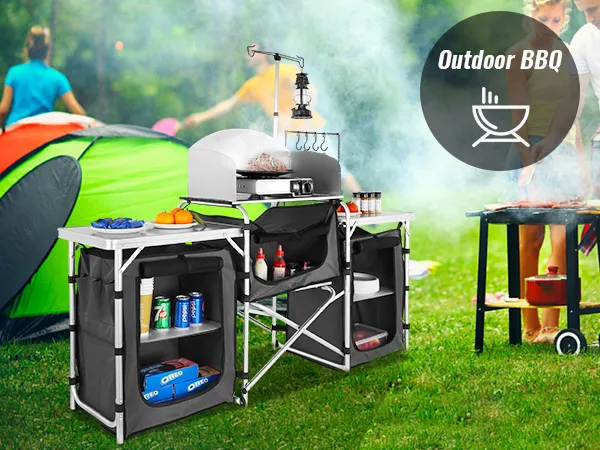 VEVOR camping kitchen table at an outdoor bbq with people grilling near a tent setup.