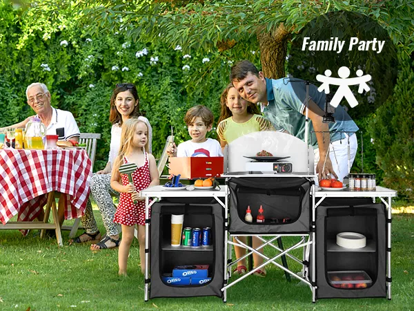 family enjoying outdoor meal with VEVOR camping kitchen table, grill, and food supplies on green lawn.