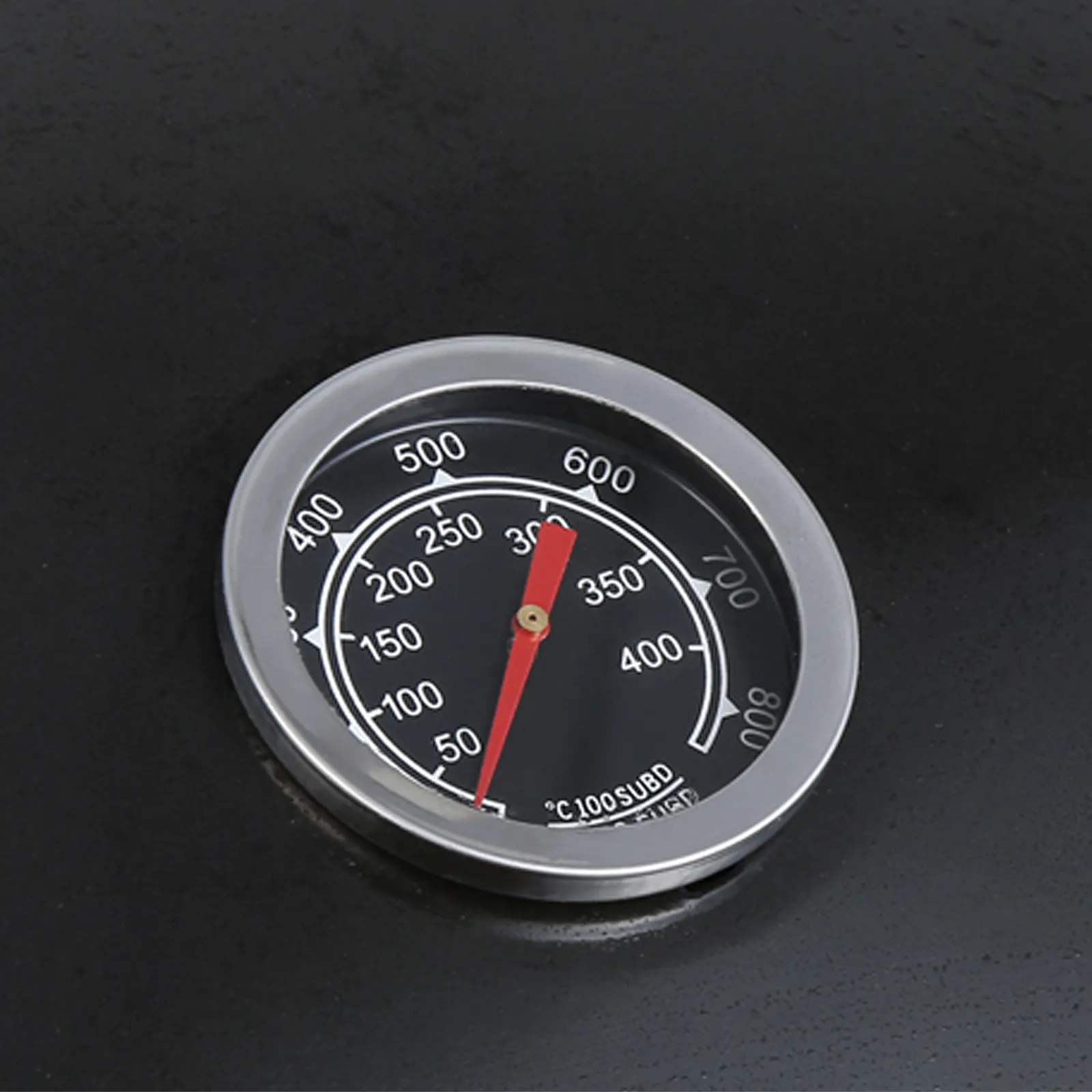 thermometer gauge on VEVOR charcoal grill displaying temperature with red needle on black background.