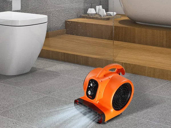 Soplador de piso VEVOR naranja sobre azulejos de baño grises, cerca de un inodoro blanco y una bañera independiente.