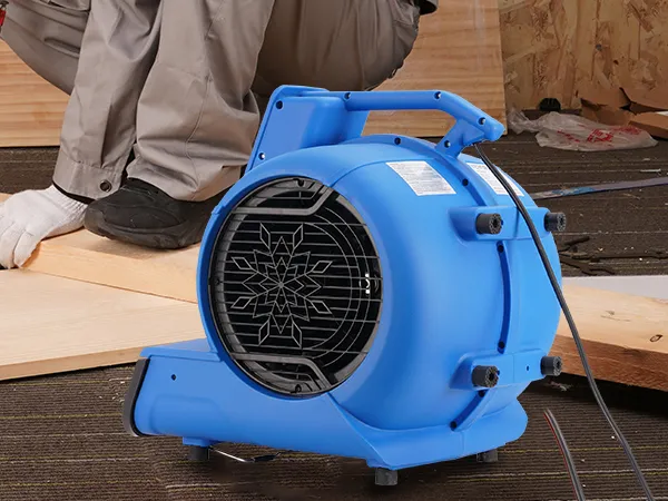 Trabajador que utiliza una sierra para madera con un soplador de suelos VEVOR en primer plano.