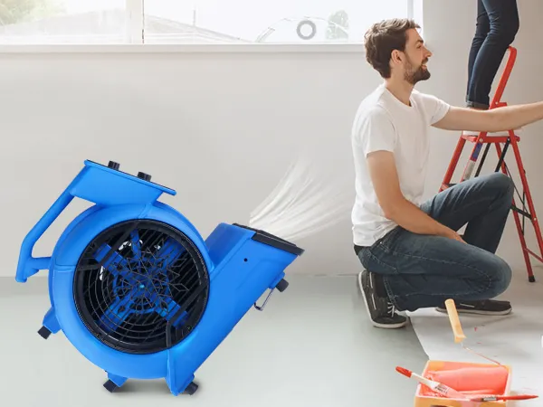 Soplador de piso VEVOR en uso durante la pintura de la pared, sofá cubierto, suministros de pintura en el piso.