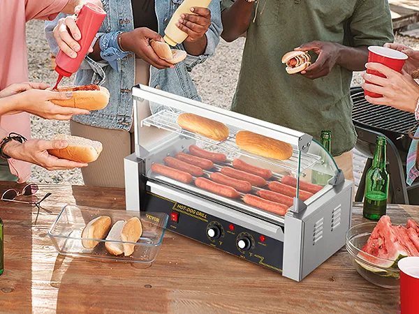 Freunde genießen ein Grillfest mit einem Hot-Dog-Roller von VEVOR und verfeinern die Hot Dogs mit Senf und Ketchup.