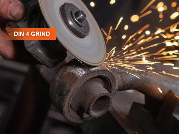worker grinding metal with an angle grinder, creating sparks, din 4 grind text visible, VEVOR welding helmet.