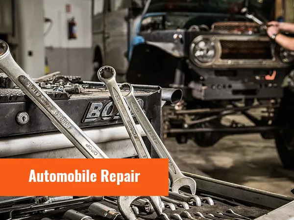 automotive repair scene with tools and wrenches in focus. technician working on vehicle in background.