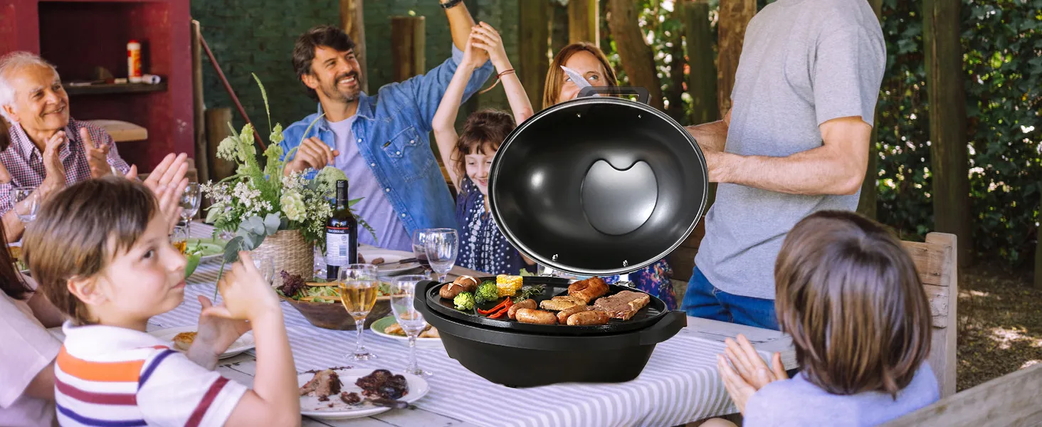 Reunión familiar alrededor de una mesa con una parrilla eléctrica VEVOR, llena de carnes y verduras a la parrilla.