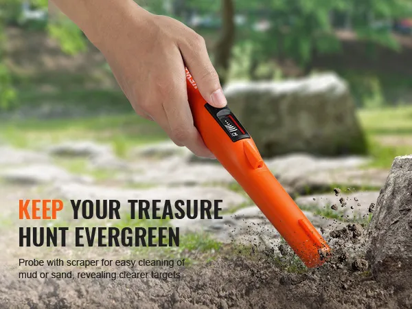mano che utilizza il puntatore del metal detector VEVOR su un terreno roccioso in una zona boscosa con rocce e vegetazione.