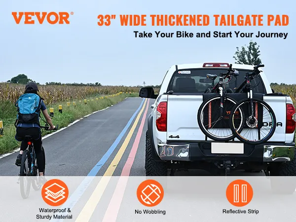 white pickup truck with VEVOR tailgate pad carrying two bikes on a country road with a cyclist.