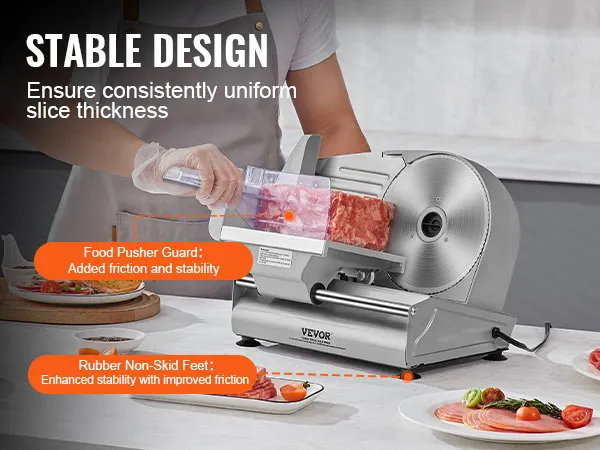Cortadora de carne VEVOR cortando carne con protector empujador de alimentos en una encimera de cocina rodeada de carne en rodajas.