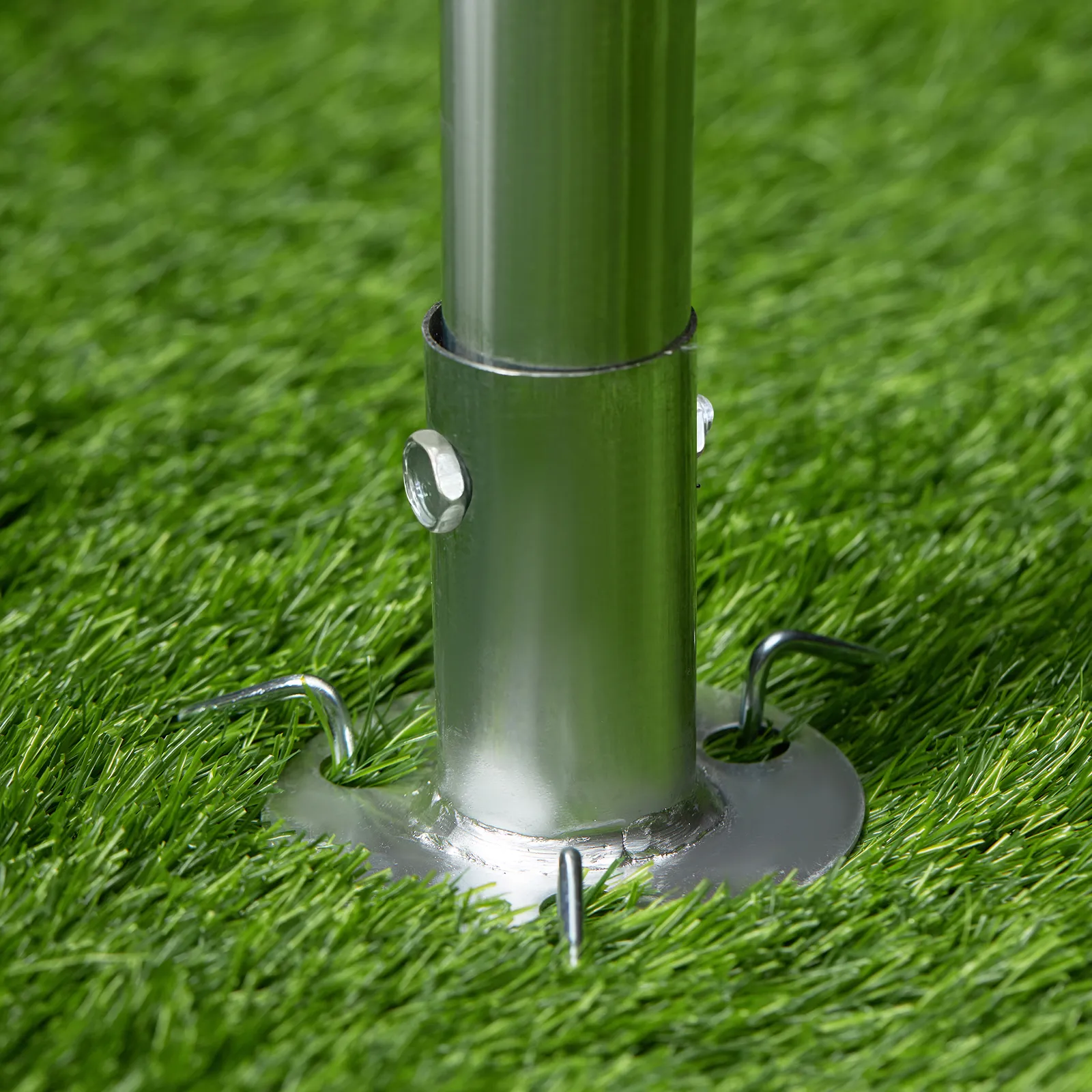 VEVOR carport metal pole embedded in green grass with anchor hooks for stability.