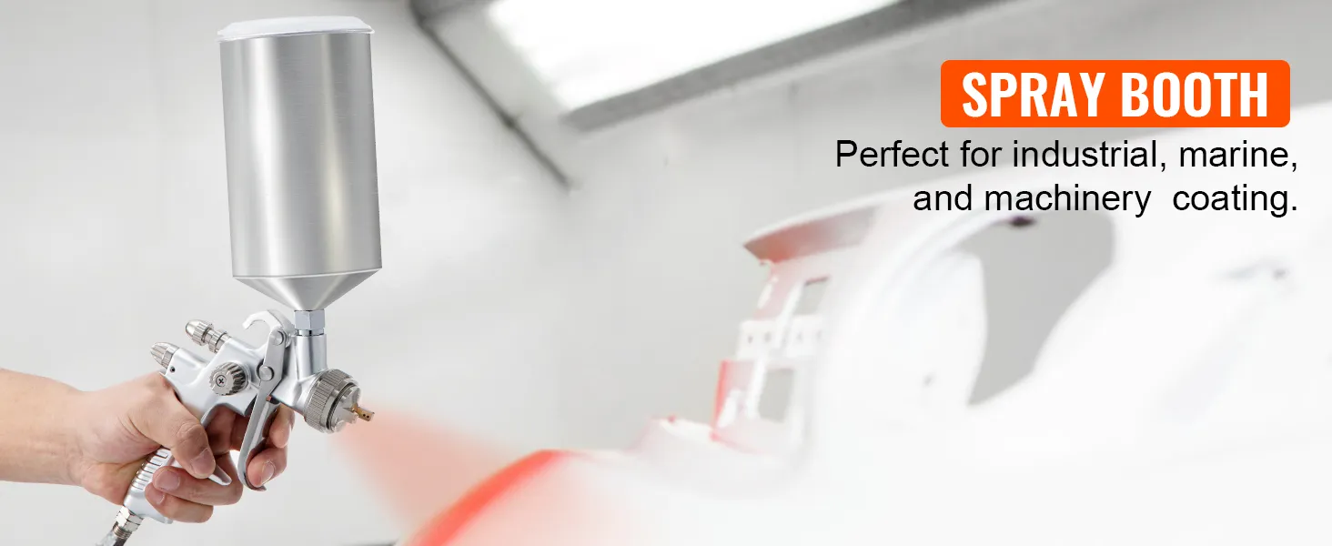 Mano sosteniendo una pistola pulverizadora de pintura para automóviles VEVOR en una cabina de pintura, ideal para recubrimiento industrial y de maquinaria.