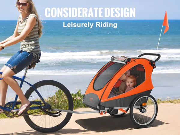 VEVOR bike trailer for toddlers being towed by a bicycle on a beachside path with scenic ocean views.
