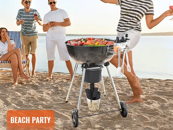 Fiesta en la playa con parrilla de carbón VEVOR, con comida de barbacoa y gente disfrutando en la orilla de arena.