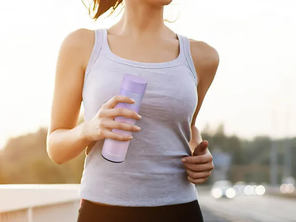woman jogging on bridge holding a purple tumbler made with VEVOR tumbler heat press.