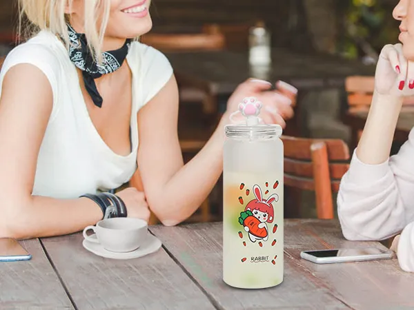 two women talking at a table with a cute rabbit-themed water bottle and smartphones.