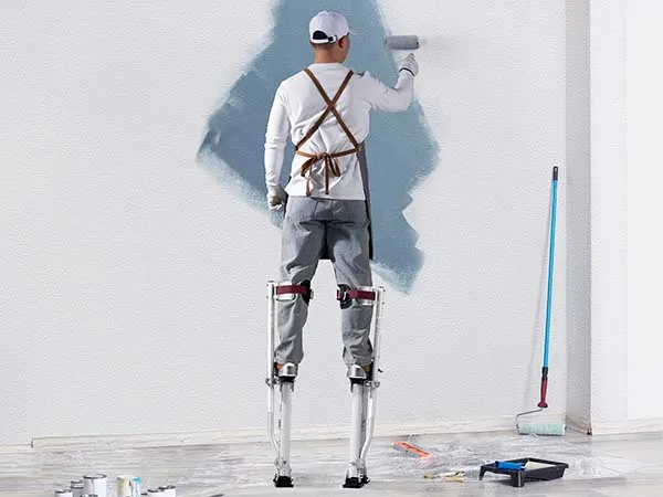 painter using VEVOR drywall stilts to paint a wall, surrounded by painting tools and supplies.