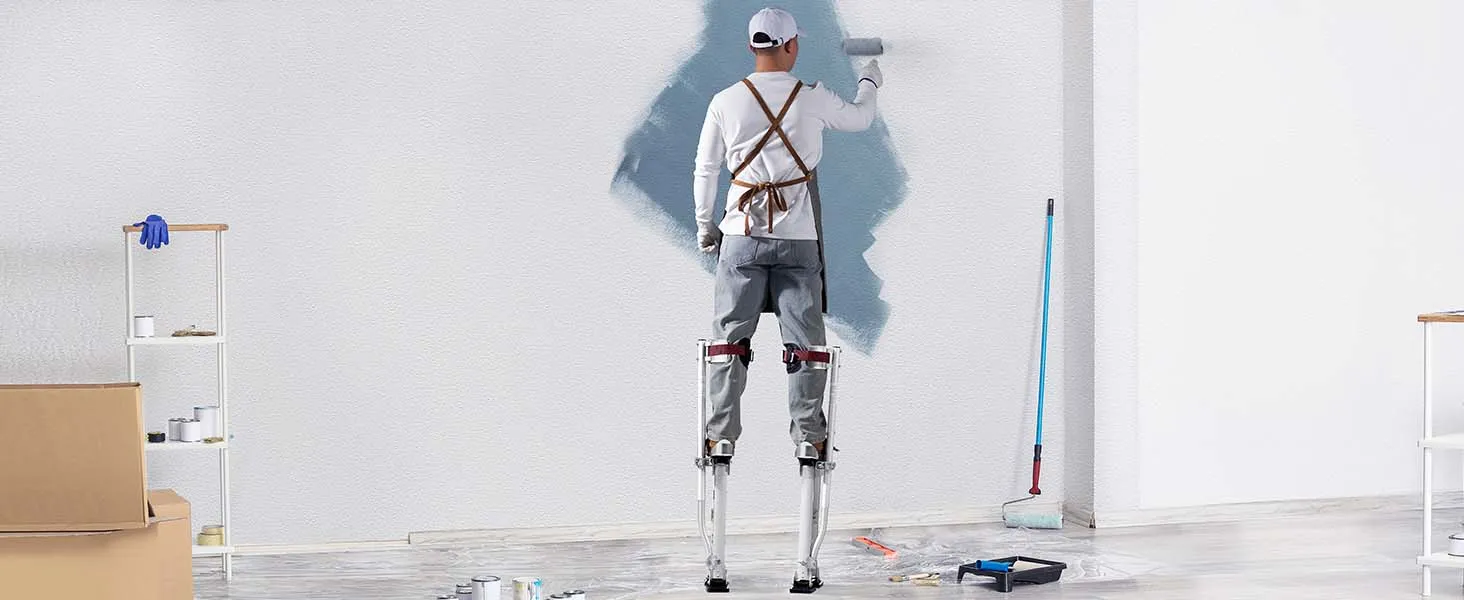 painter using VEVOR drywall stilts to paint a wall, surrounded by painting tools and supplies.