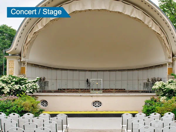 outdoor concert stage setup with chairs, trees, and VEVOR cable protector ramp near stage.