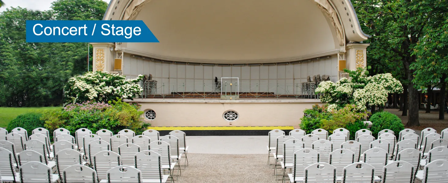 outdoor concert stage setup with chairs, trees, and VEVOR cable protector ramp near stage.