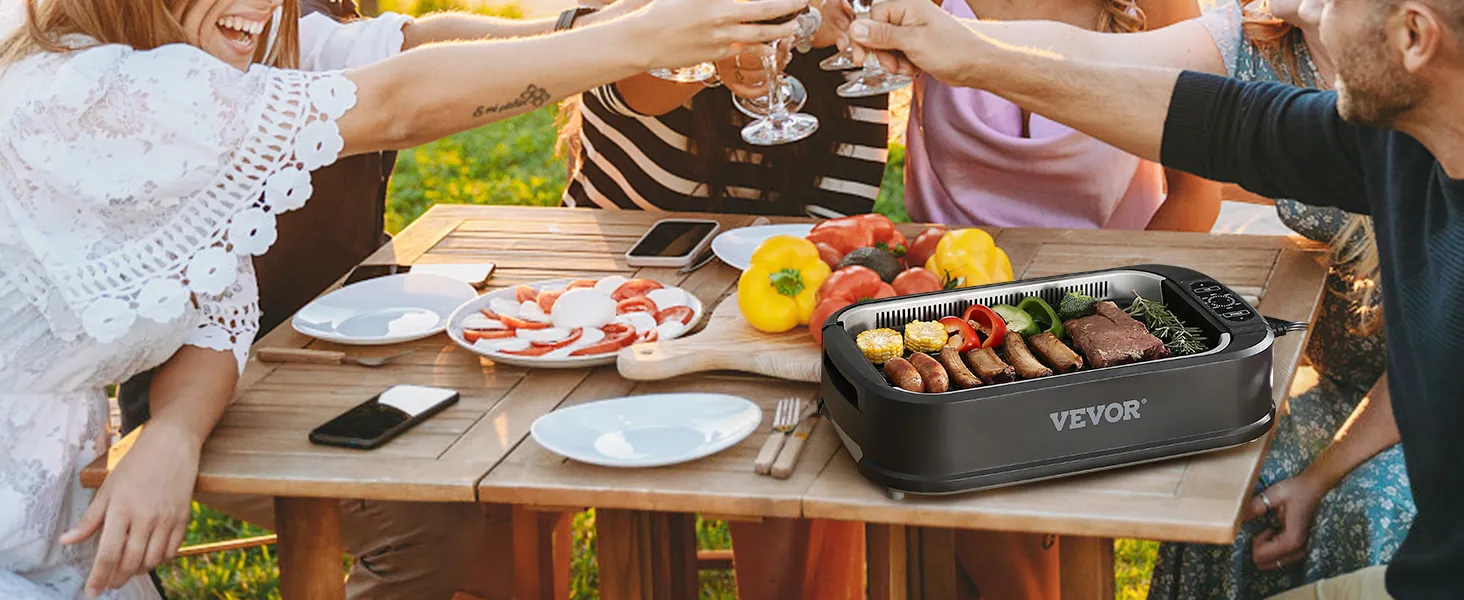 Grupo de amigos disfrutando de una comida con una parrilla interior sin humo VEVOR en una mesa de madera al aire libre.