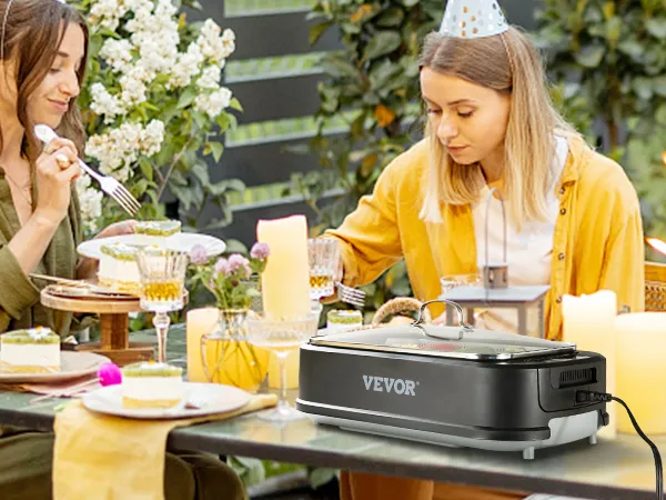 Reunión al aire libre con amigos utilizando la parrilla interior sin humo VEVOR sobre una mesa de azulejos verdes adornada con velas.