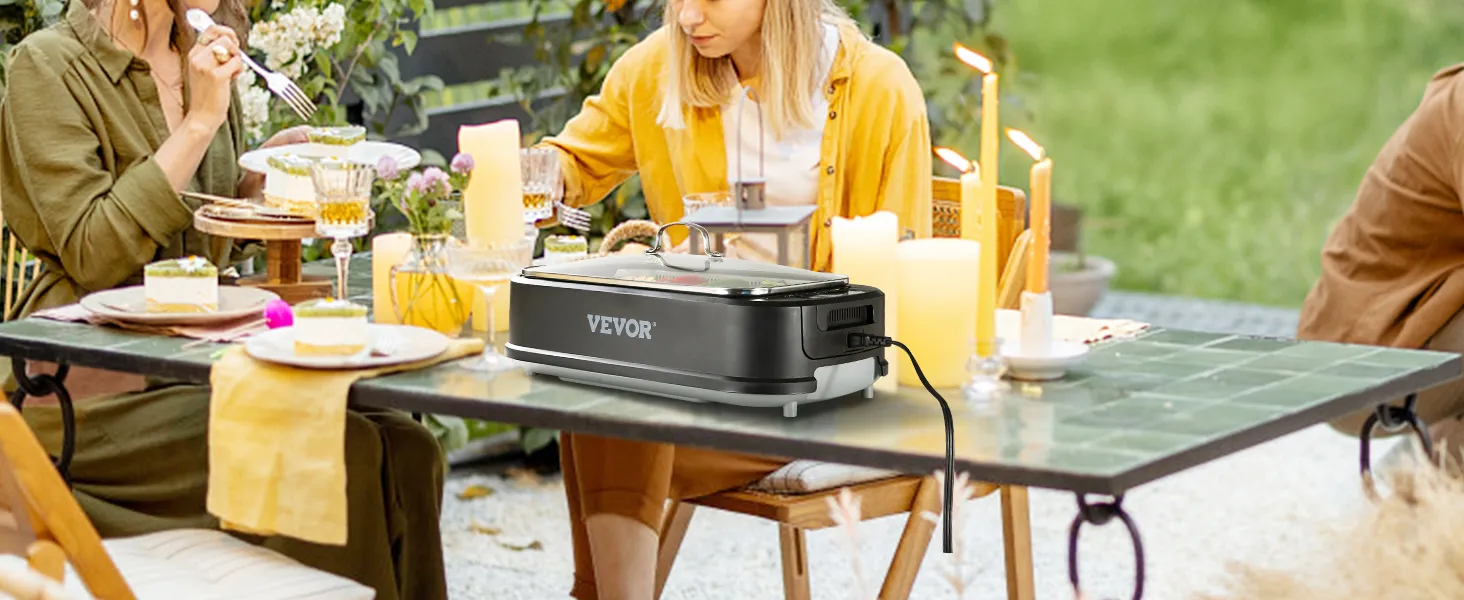 Reunión al aire libre con amigos utilizando la parrilla interior sin humo VEVOR sobre una mesa de azulejos verdes adornada con velas.