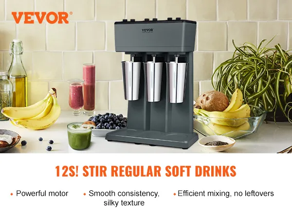 Máquina para hacer batidos VEVOR con tres tazas de acero inoxidable, frutas y bebidas sobre la encimera de la cocina.