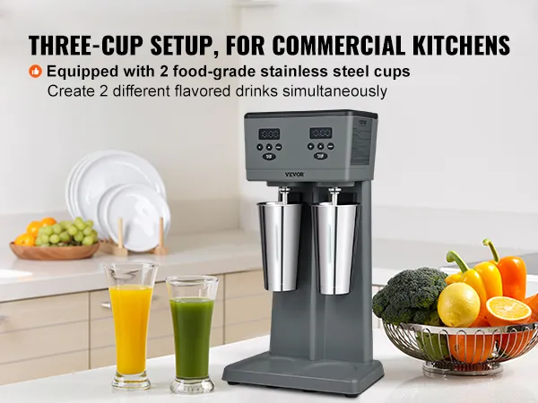 Máquina para hacer batidos VEVOR con dos tazas de acero inoxidable en una cocina moderna, rodeada de fruta fresca.
