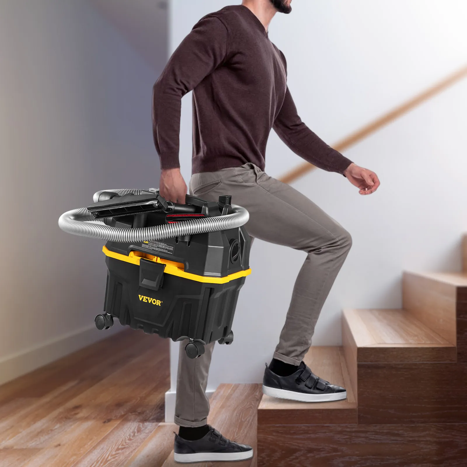 Persona llevando una aspiradora de taller VEVOR arriba, mostrando portabilidad y diseño liviano.