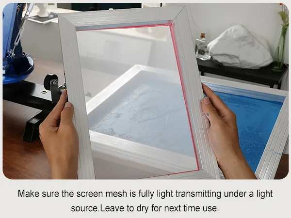 hands holding a screen printing frame near a VEVOR screen printing kit, preparing to dry.