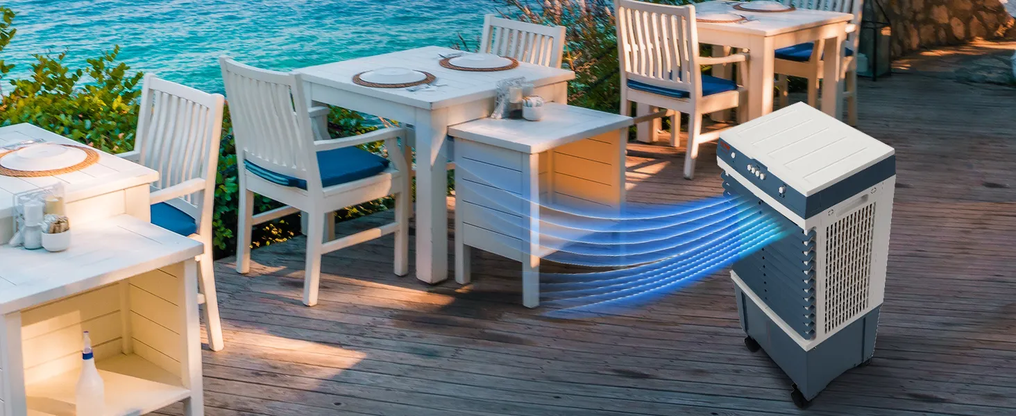Enfriador evaporativo VEVOR en una terraza de madera cerca del océano, enfriando un área de comedor al aire libre con muebles blancos.