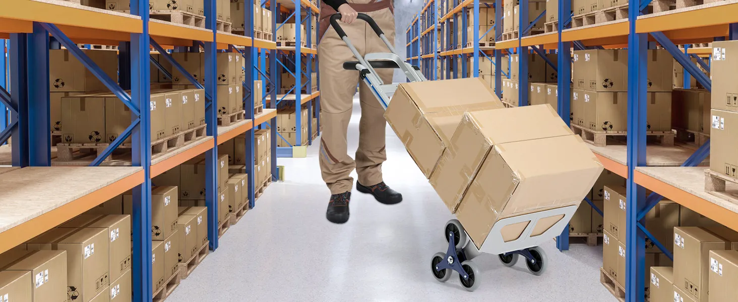 Un trabajador del almacén utiliza un carrito sube escaleras VEVOR para mover cajas a través de estantes de metal llenos de paquetes.