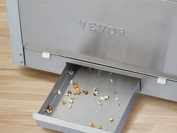 VEVOR popcorn popper machine with open drawer and scattered popcorn kernels on light wooden surface.