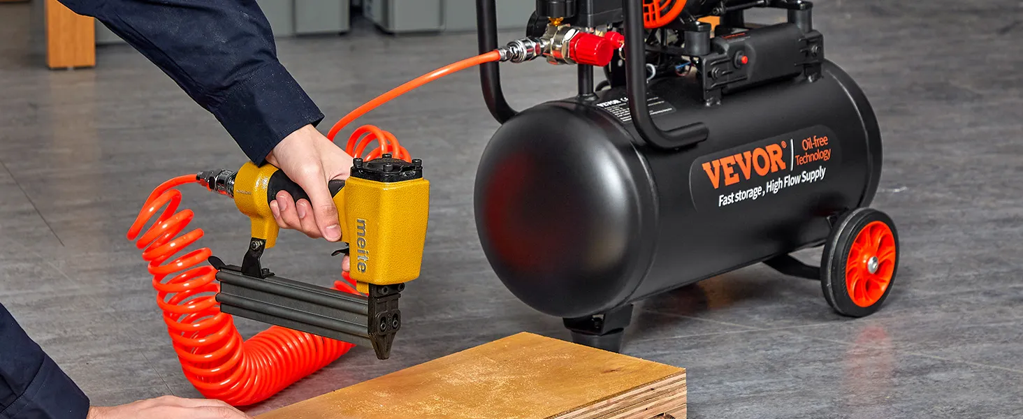 Persona que utiliza una pistola de clavos conectada a un compresor de aire ultra silencioso VEVOR con una manguera naranja enrollada.