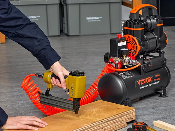 using a nail gun connected to a VEVOR ultra quiet air compressor with coiled orange hose.