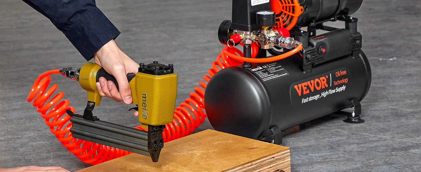 using a nail gun connected to a VEVOR ultra quiet air compressor with coiled orange hose.